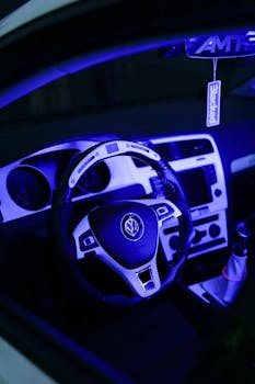 A Volkswagen car interior featuring a sleek dashboard and steering wheel with ambient blue lighting.