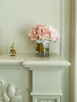 A serene and elegant interior featuring a vase of pink roses on a classic mantelpiece.