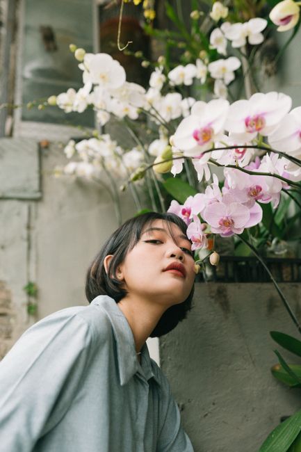A woman admires vibrant orchids outdoors, blending nature and elegance.