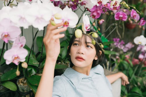 

A Woman in a Gray Top Looking at Orchid Flowers