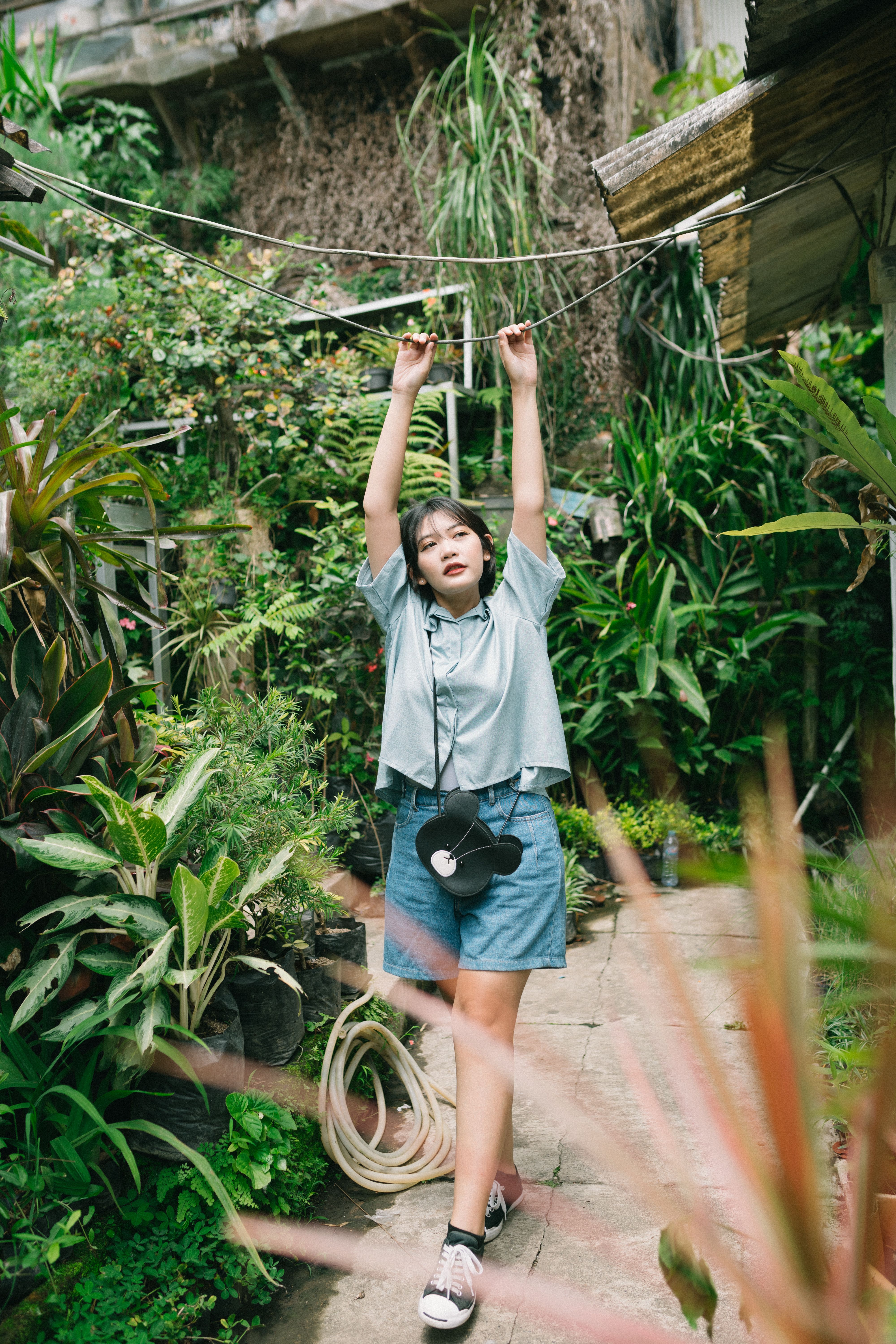 Young woman with arms raised enjoying a walk in a lush tropical garden during summer.