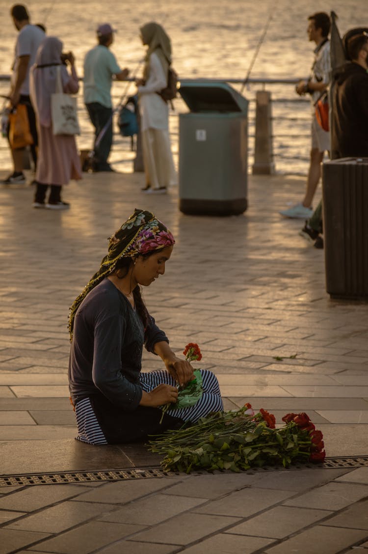 A Woman Sitting On The Floor Holding Red Roses