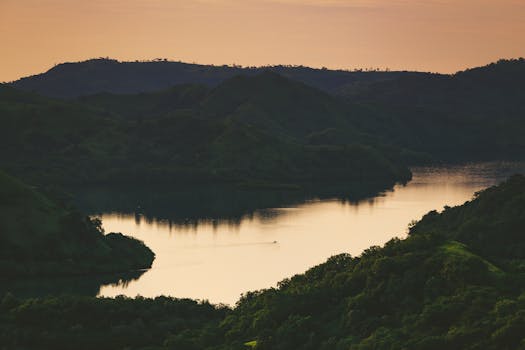 俯瞰湖泊，倒映着郁郁葱葱山丘的印度尼西亚日落宁静而美丽
