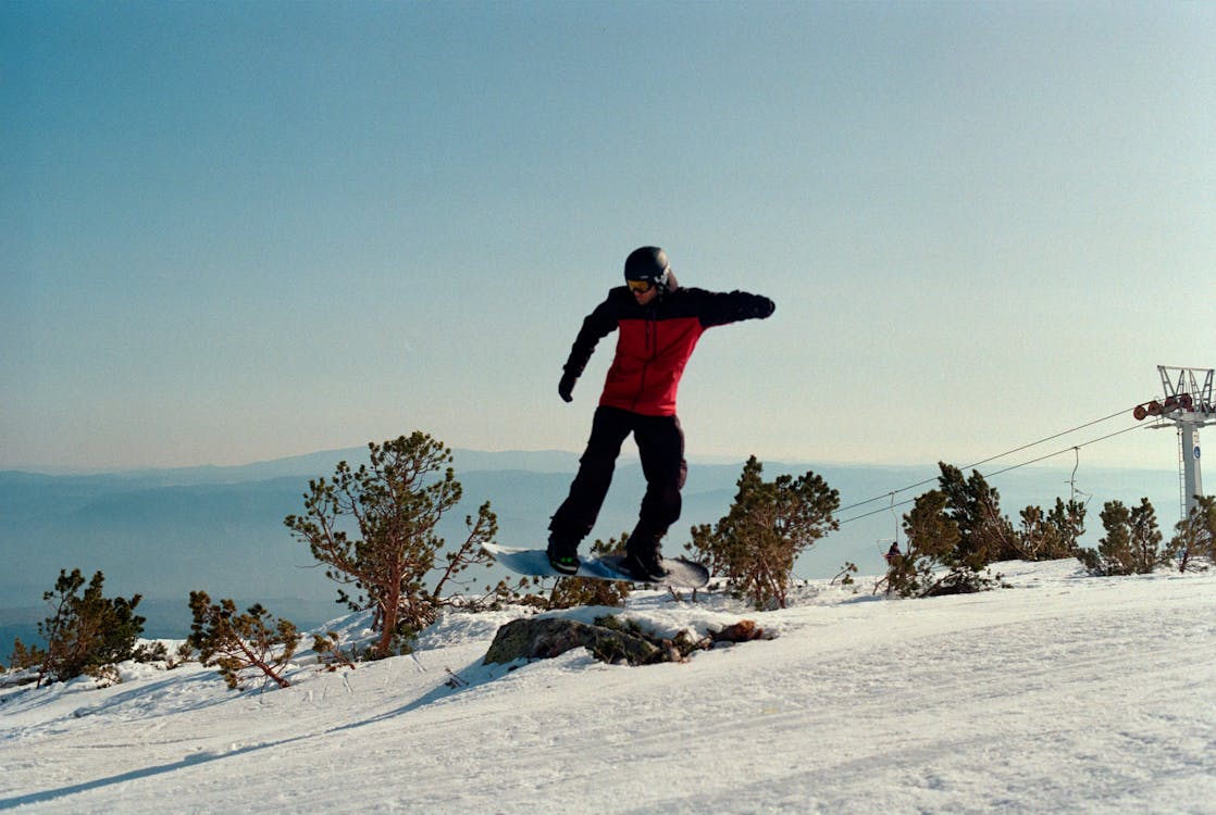 Free Person on Snowboard Jumping Over a Rock Stock Photo