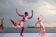 日落时分，一群舞者在自由女神像前的海边表演