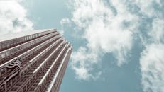 低角度视角下的现代摩天大楼，背景是美国国旗和多云的天空