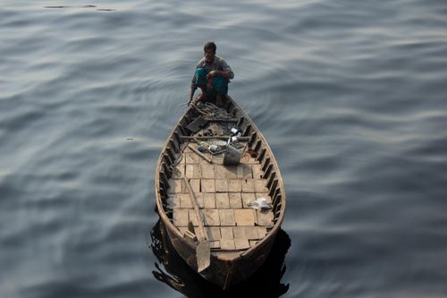 Free Aerial view of a man in a wooden boat on a calm lake, reflecting tranquility. Stock Photo