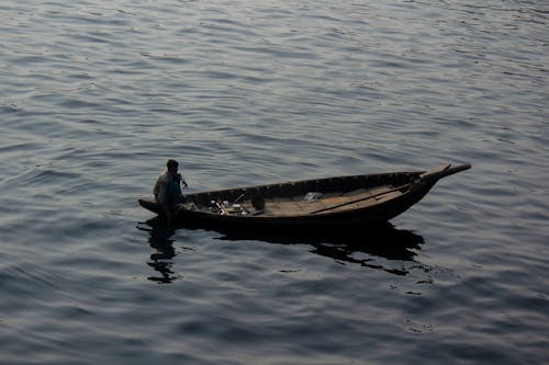 Man Sitting on a Fishing Boat on Sea