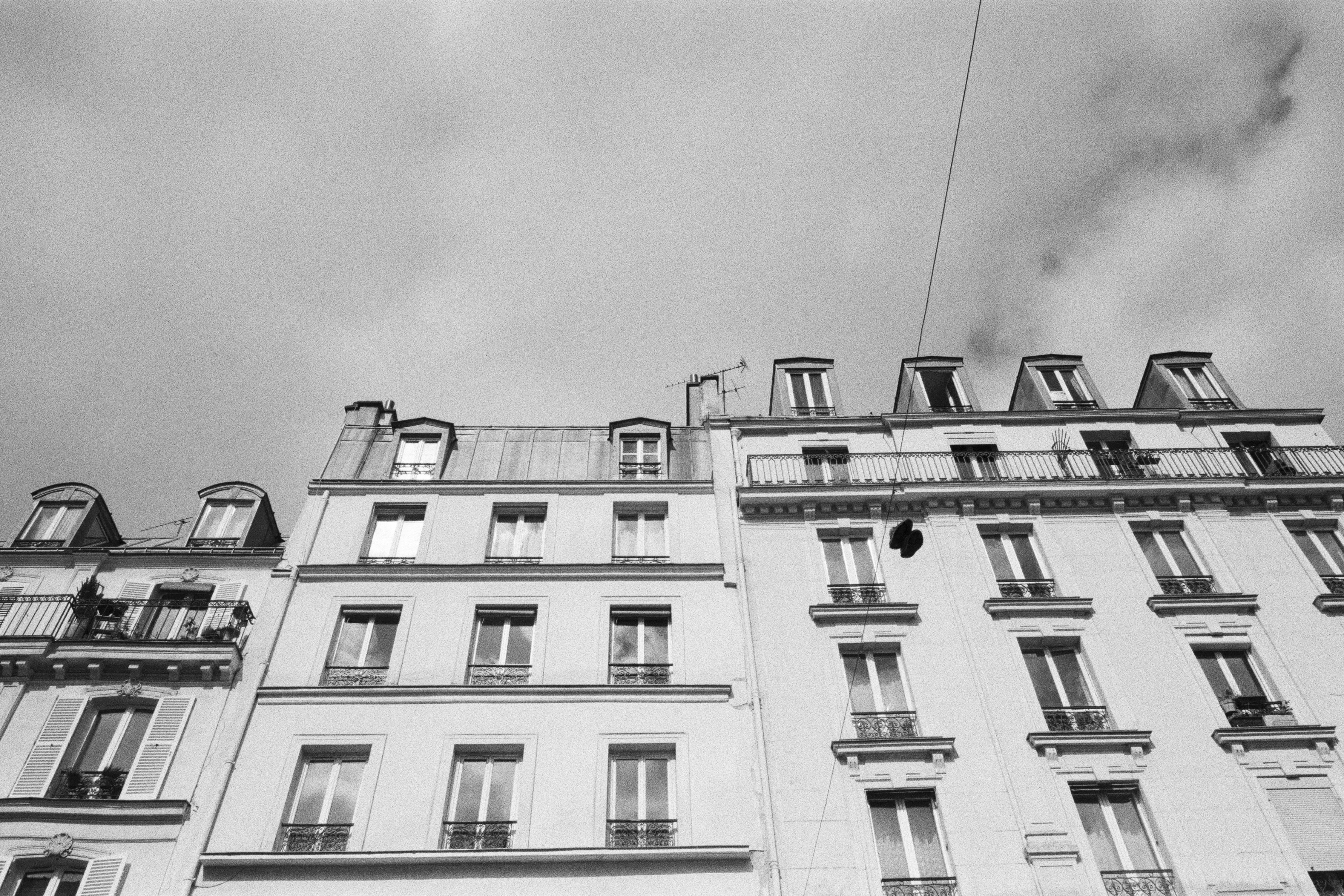 Low angle view of Parisian building facade in monochrome with a cloudy sky background.