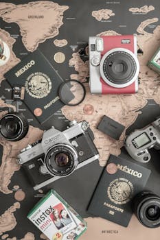 Artistic flat lay of cameras, Mexican passports, and travel items on a world map.