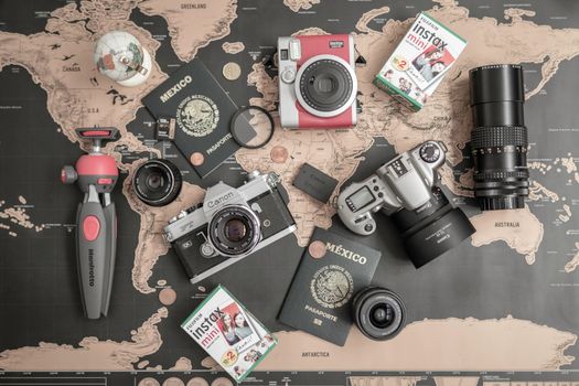 Flat lay of vintage cameras, passports, and travel essentials on a world map.