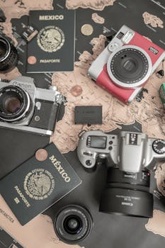 Flat lay of cameras and Mexican passports on a world map, perfect for travel themes.