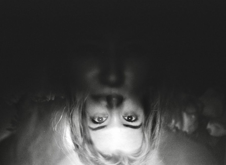 Eerie black and white photo with upside down woman's face in shadow.