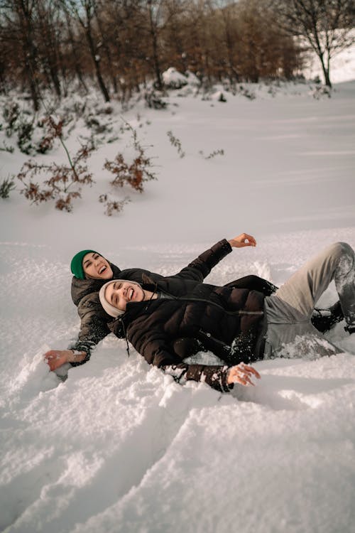 Smiling Couple Lying in Snow in Park