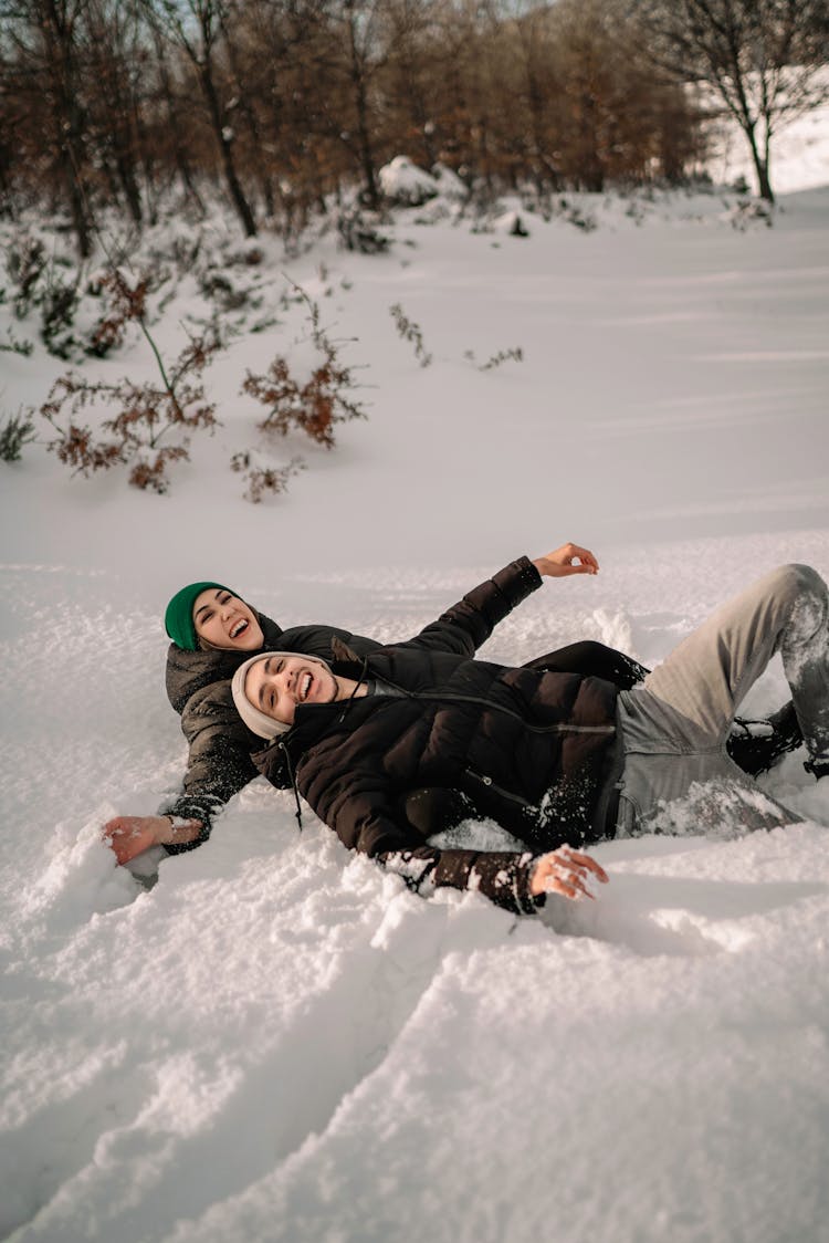 Smiling Couple Lying In Snow In Park