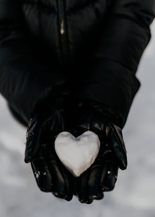 Close-up of Person in Gloves Holding Snow Heart in Hands
