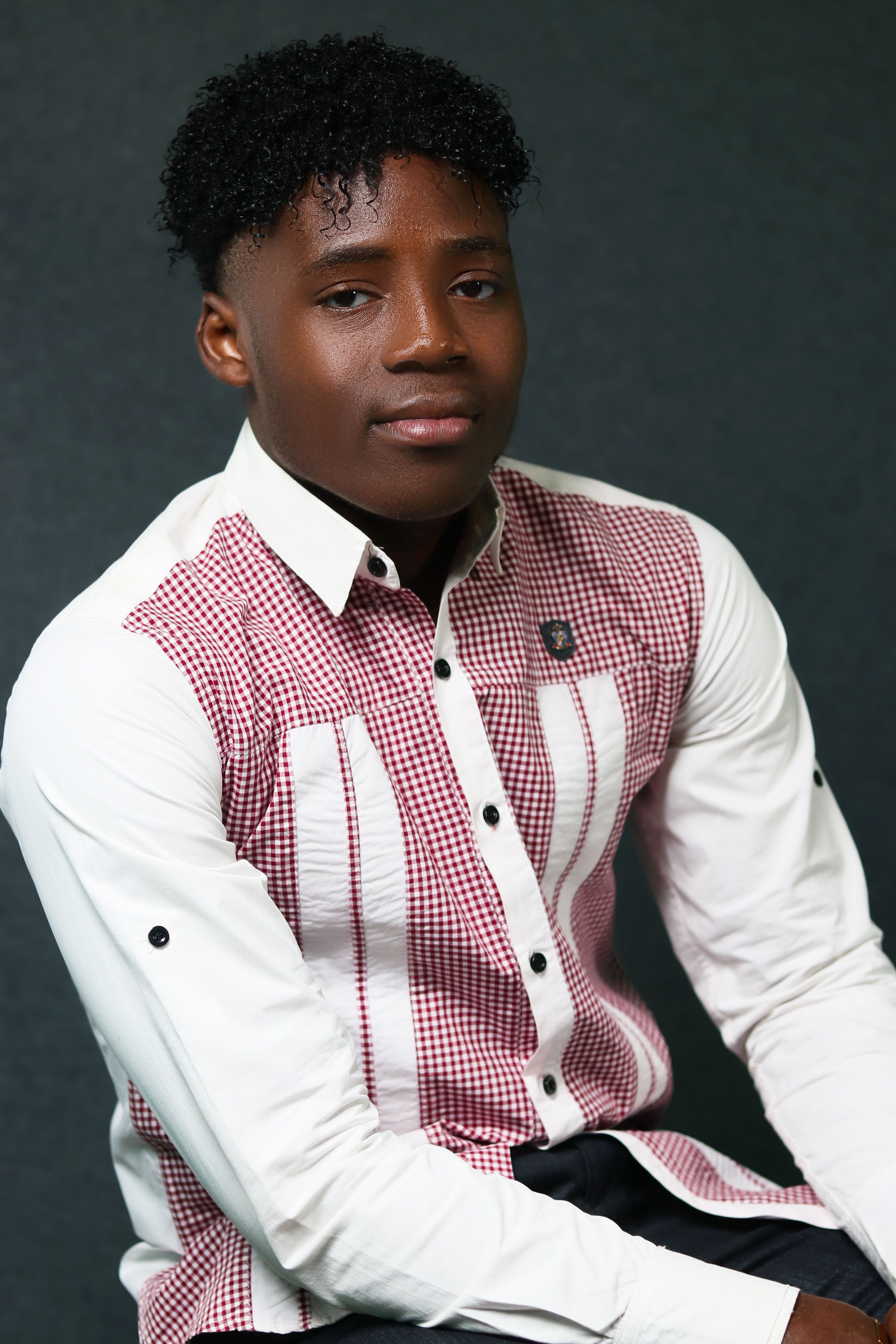 Portrait of a young man in stylish attire, captured in a studio setting with a neutral background.