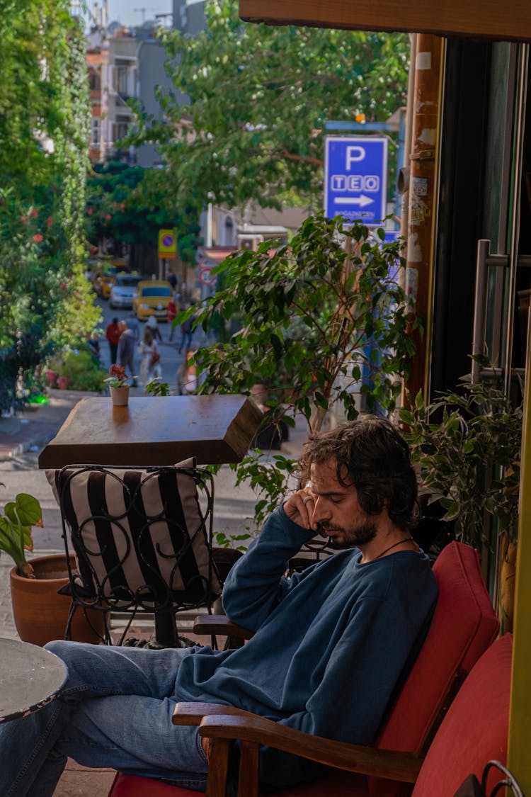 A Man In Blue Sweater Sitting On A Chair