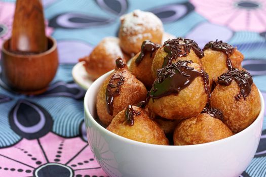 Tasty puff pastries drizzled with chocolate in a decorative bowl, perfect for dessert lovers.