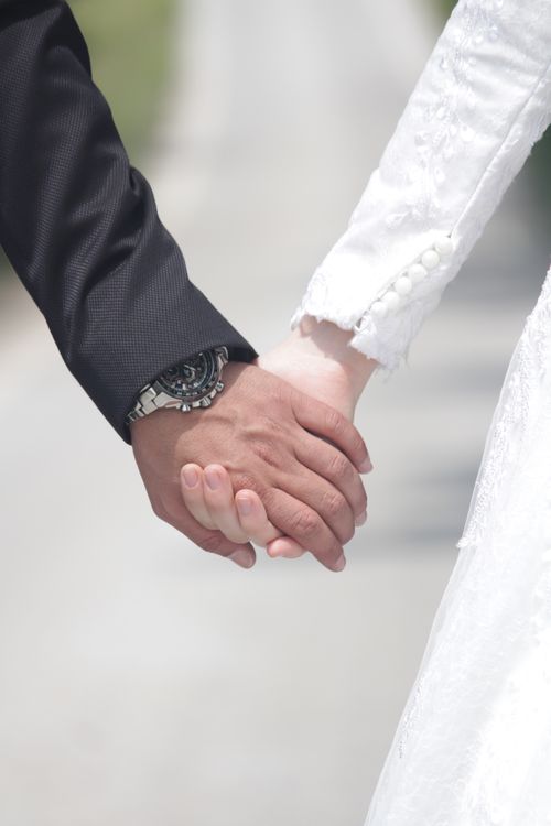 Free Elegant close-up of a bride and groom holding hands, symbolizing love and unity. Stock Photo