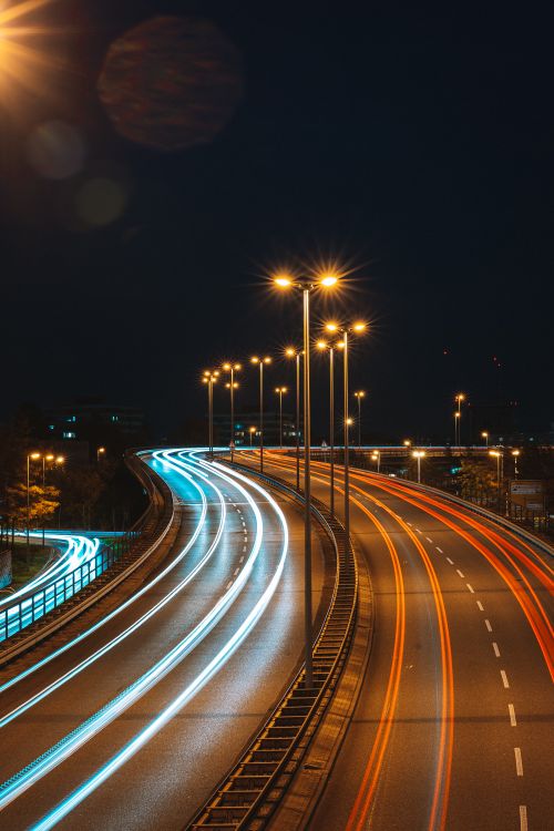 Free Long exposure capturing light trails on an urban highway at night with street lights. Stock Photo