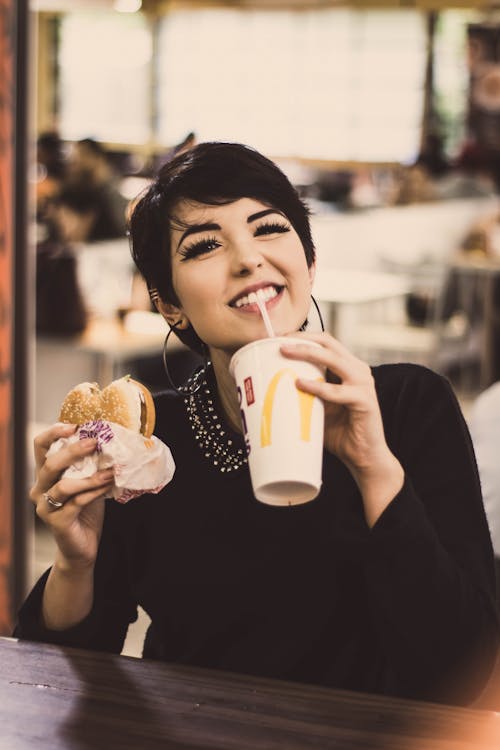 A Woman Holding Hamburger and Drink