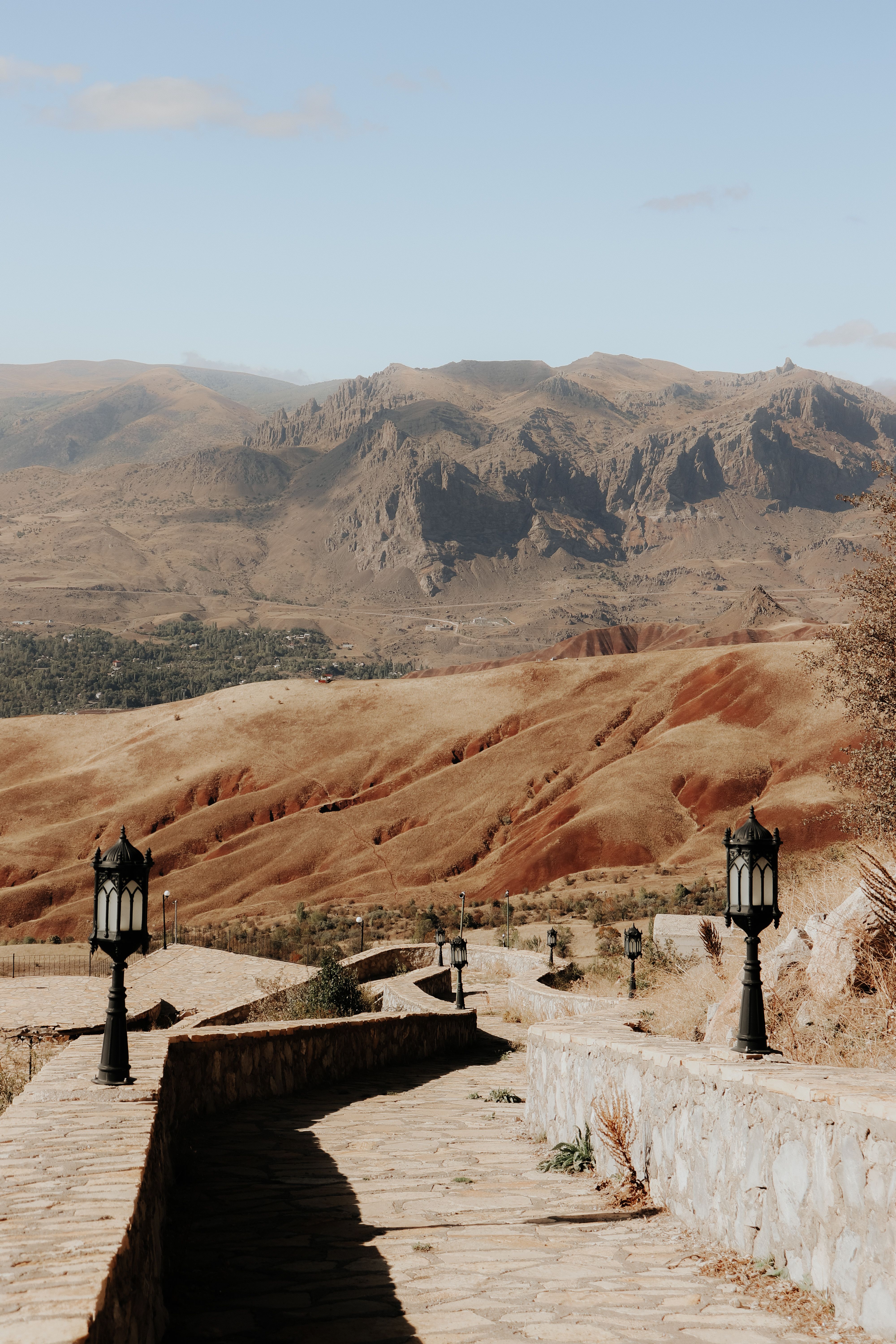 A serene landscape featuring a stone walkway leading through a rugged mountain range under a clear sky.