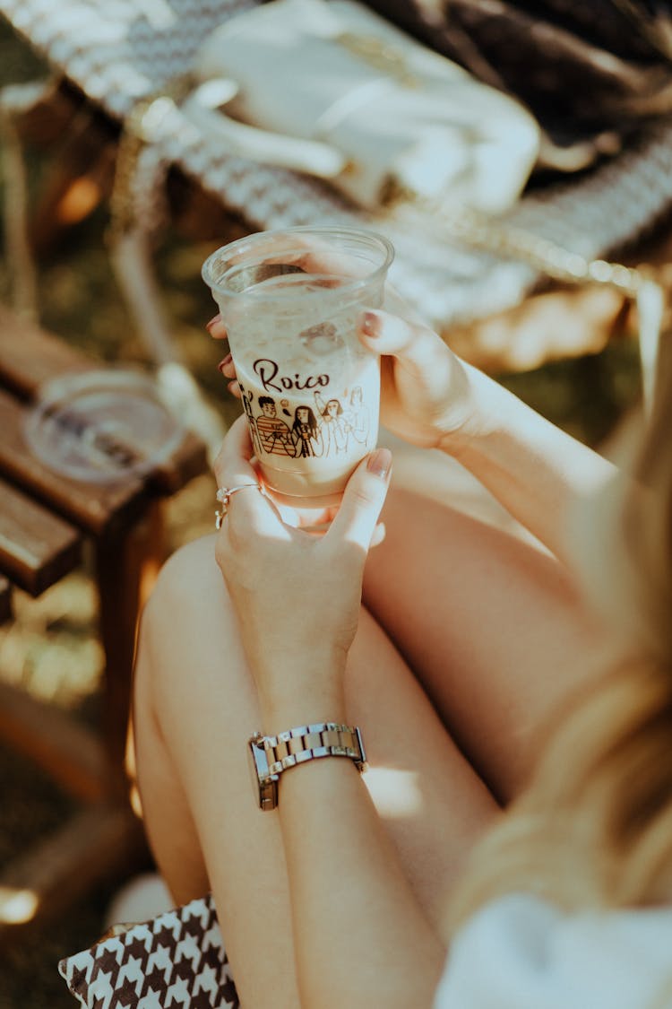 Person Sitting And Holding Disposable Plastic Cup