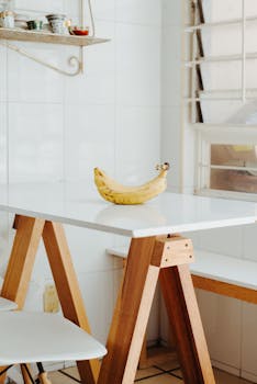 A minimalist kitchen setting featuring a single banana on a white table.