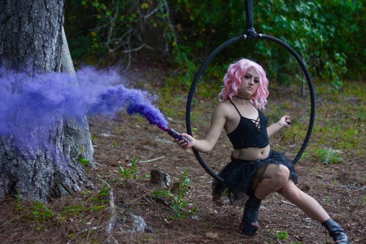 A Woman On A Swing Holding A Smoke Bomb