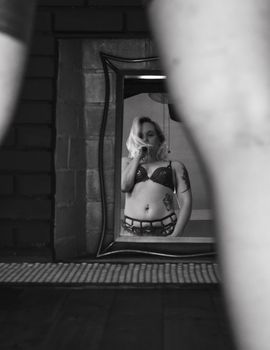 Artistic black and white portrait of a woman in a mirror, featuring intriguing reflection.