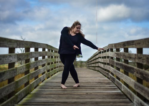 Woman Dancing on Wooden Bridge