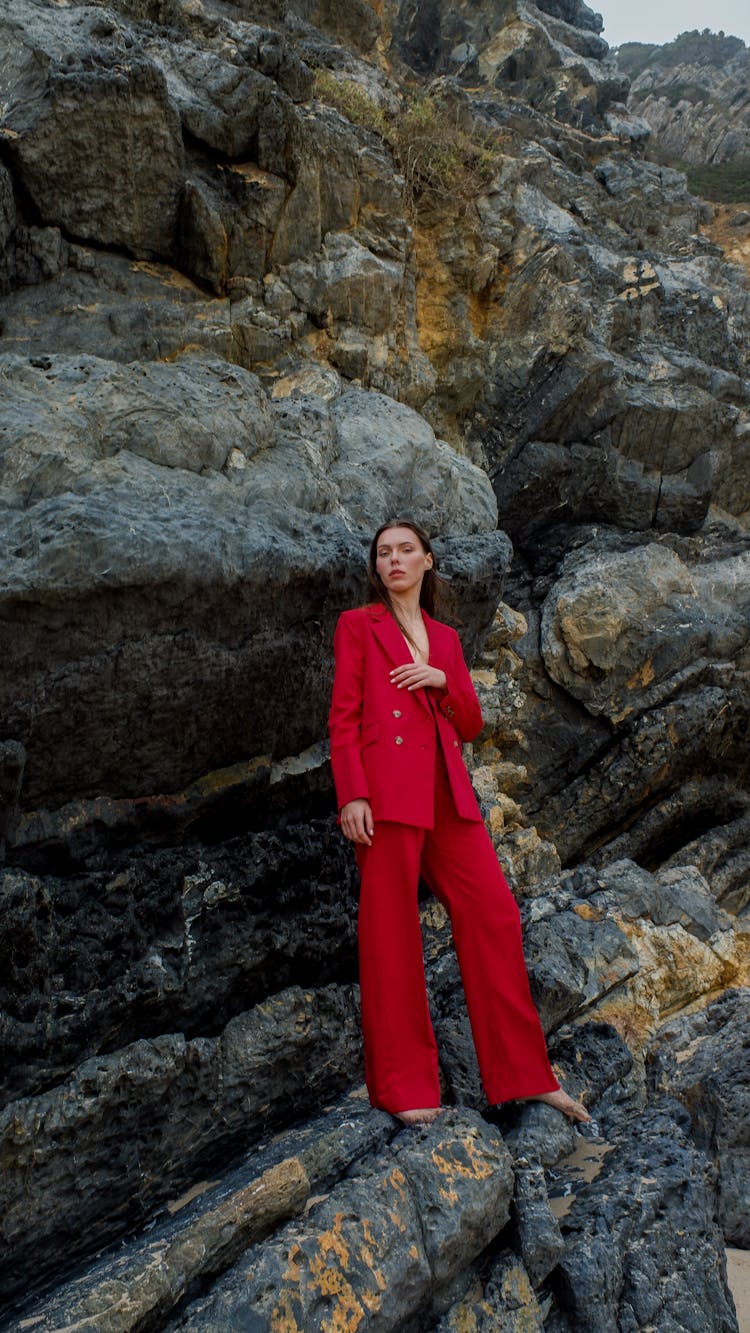 A Woman In Red Suit Standing On Rocks