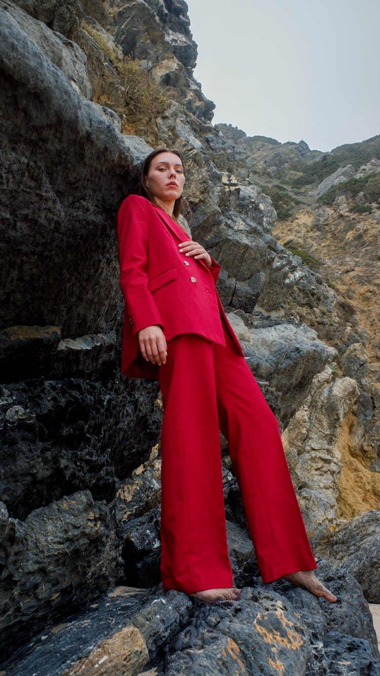 A Woman In Red Suit Standing On Rocks
