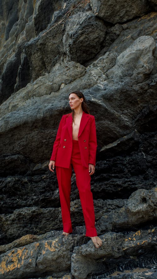 Woman Wearing Red Suit while Standing on the Rock