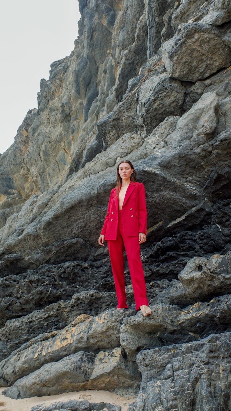 A Woman In Red Suit Standing On Rocks
