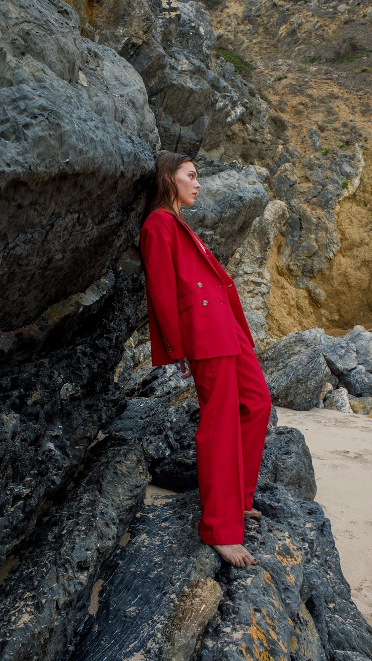 A Woman In Red Suit Standing On Rocks
