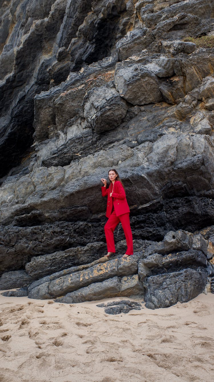 A Woman In Red Suit Standing On Rocks
