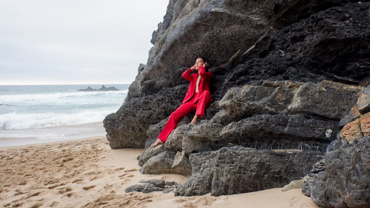 A Person In Red Suit Sitting On Rocks
