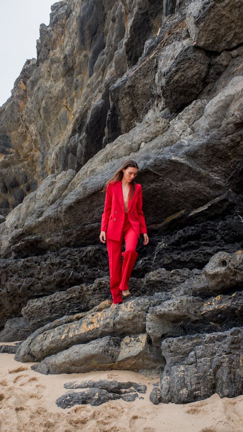 Woman Wearing Red Suit while Standing on the Rock

