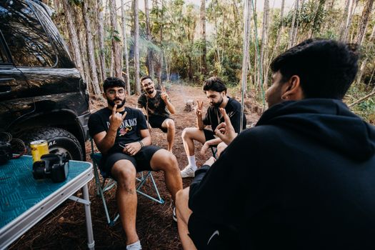 Four men sitting and chatting during a daytime camping trip in the forest.