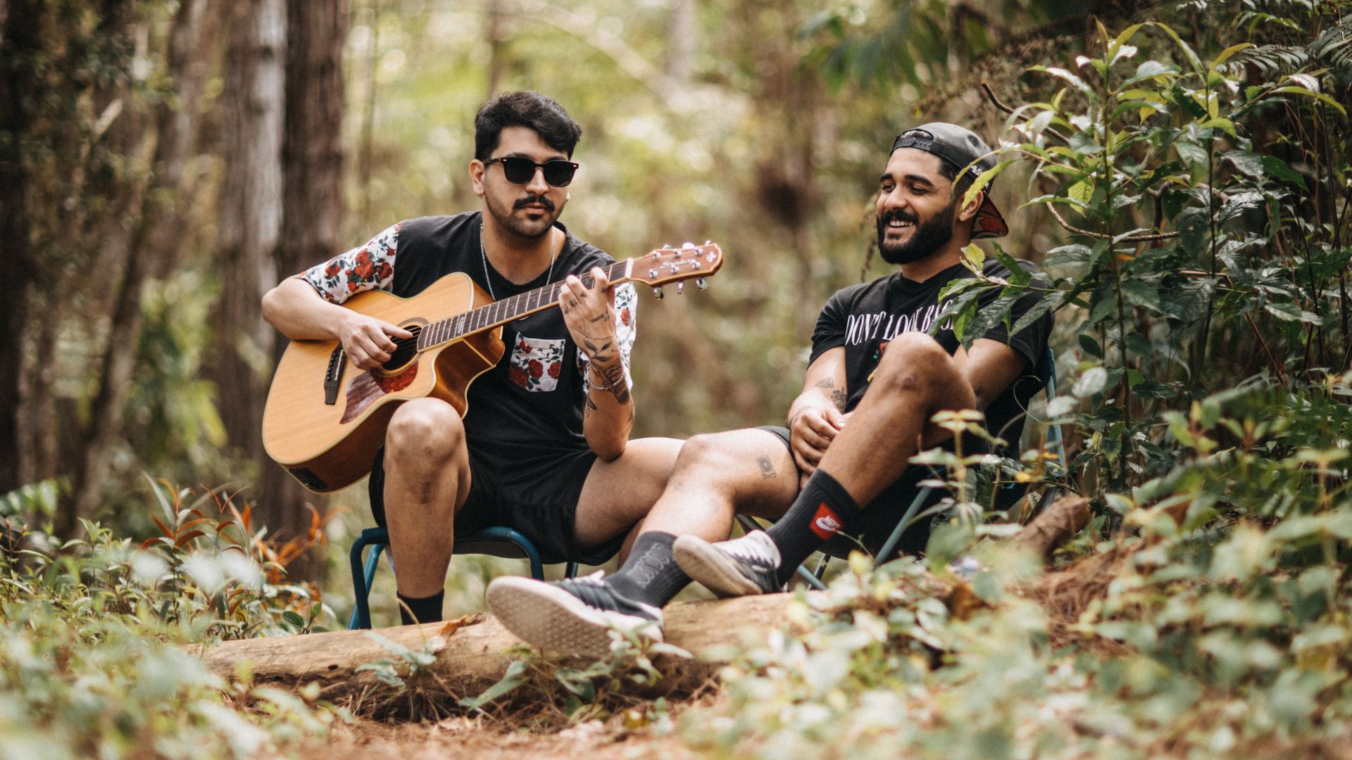 Modafinil for Musicians on Tour: Unleash Creativity Two men enjoy a musical moment with a guitar in a scenic forest setting — modafinil for musicians on tour