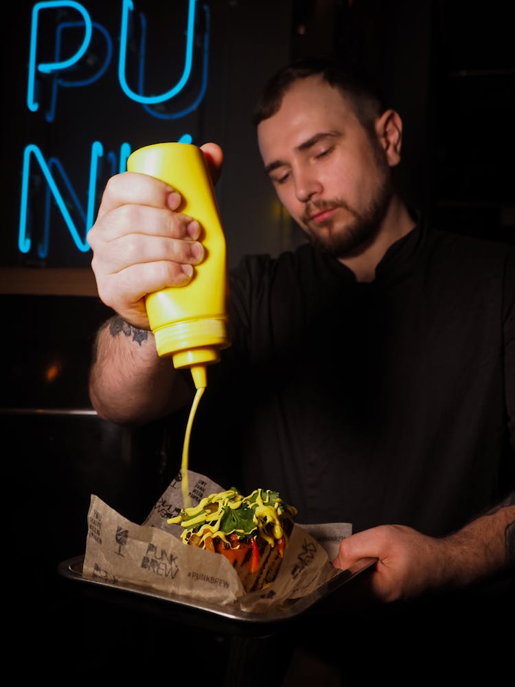 Man Putting Sauce On A Burger