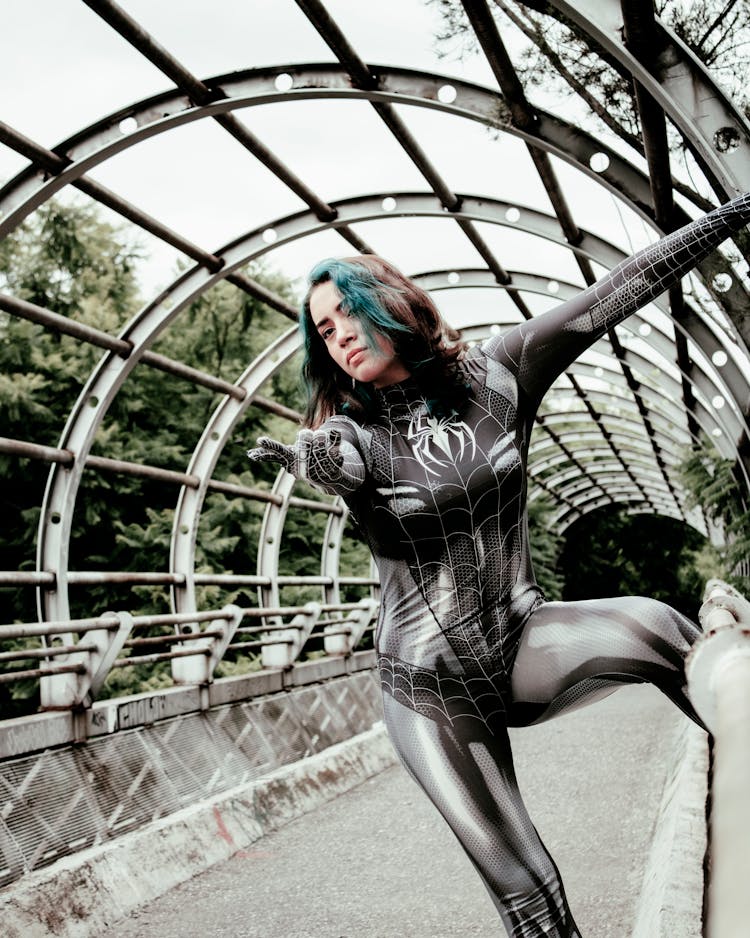 A Woman Wearing Black Spiderwoman Costume Standing On Footbridge