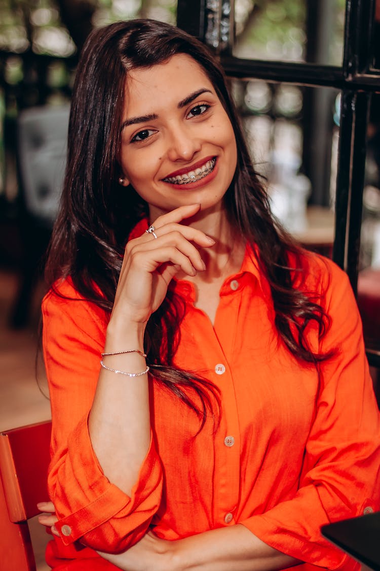 A Woman In Orange Dress Shirt Smiling