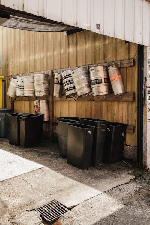 Stainless Barrels Hanging Above Black Trash Bins