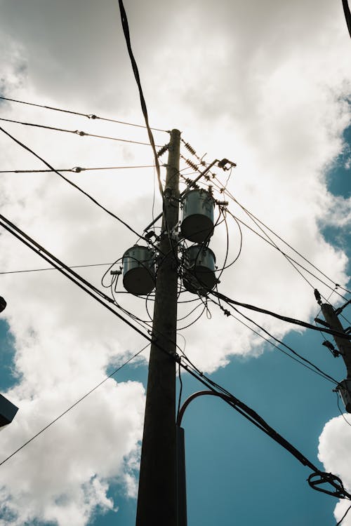 An Electric Power Pole with Wires and Transformers Under White Clouds