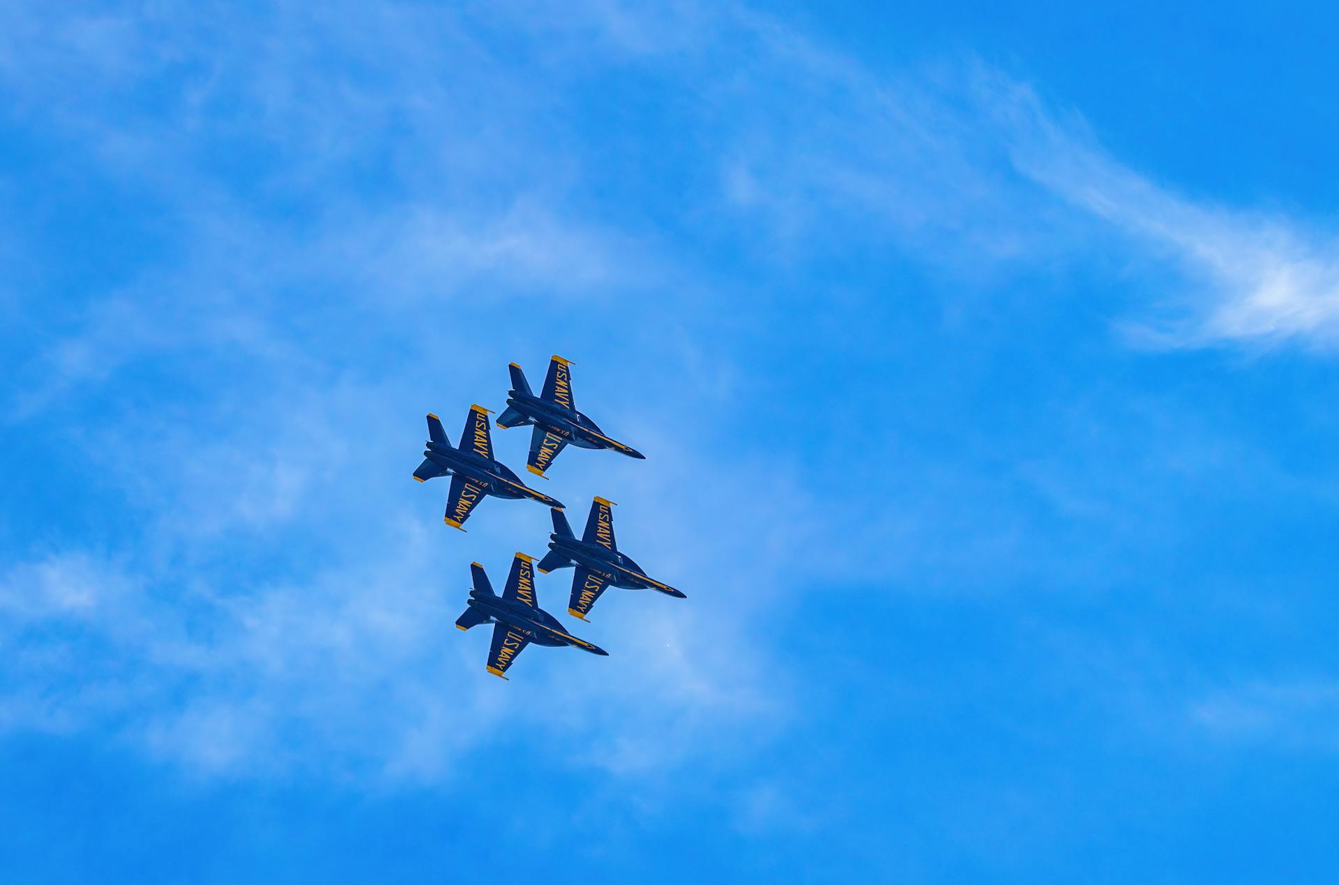 Four fighter jets in a precision aerial formation against a bright blue sky, showcasing aviation excellence.