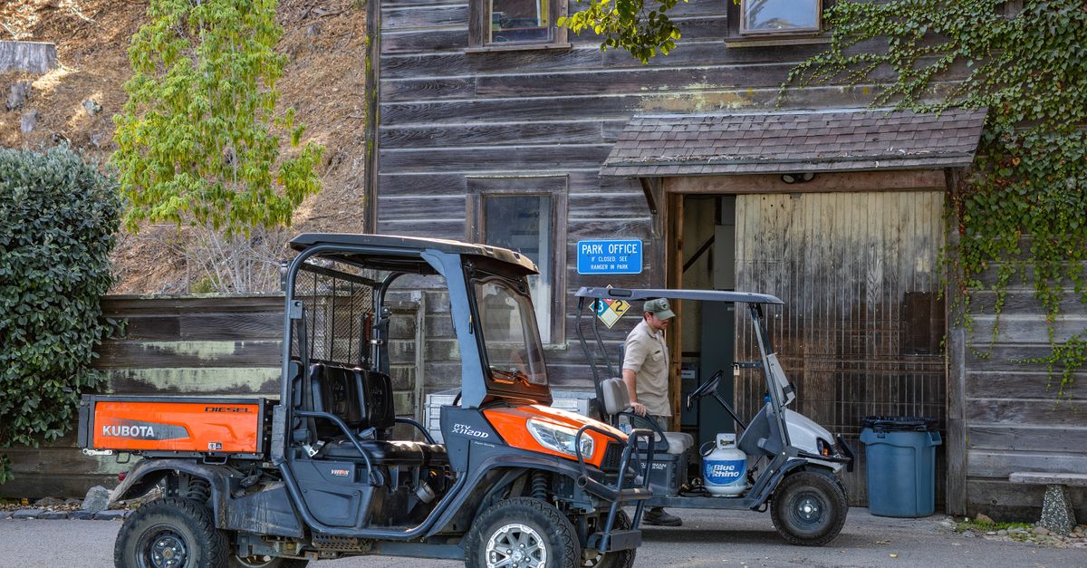 Rustic park office entrance with utility vehicles parked outside on a sunny day.