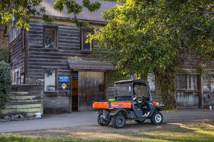 A Black And Orange Utility Vehicle Parked Beside Wooden Building